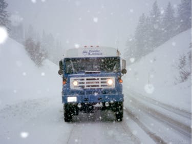 The front of a Powder Mountain shuttle on a snowy road in a snowstorm