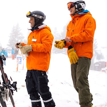 Two Powder Mountain employees smile and converse with someone out of frame