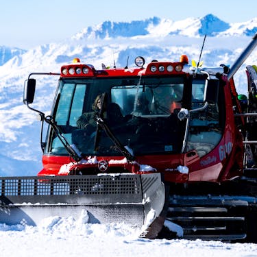 A group of skiers ride in the back of a snowcat