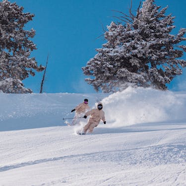 A skier and snowboarder riding powder