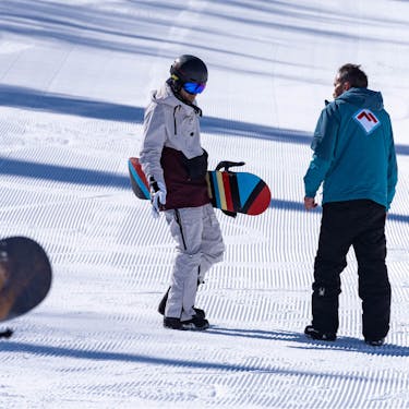 An instructor talks to a snowboarder