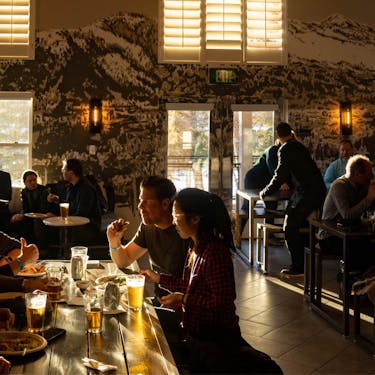 People enjoy beers and food at restaurant filled with warm light