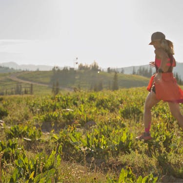A woman runs through a hilltop trail in the sun