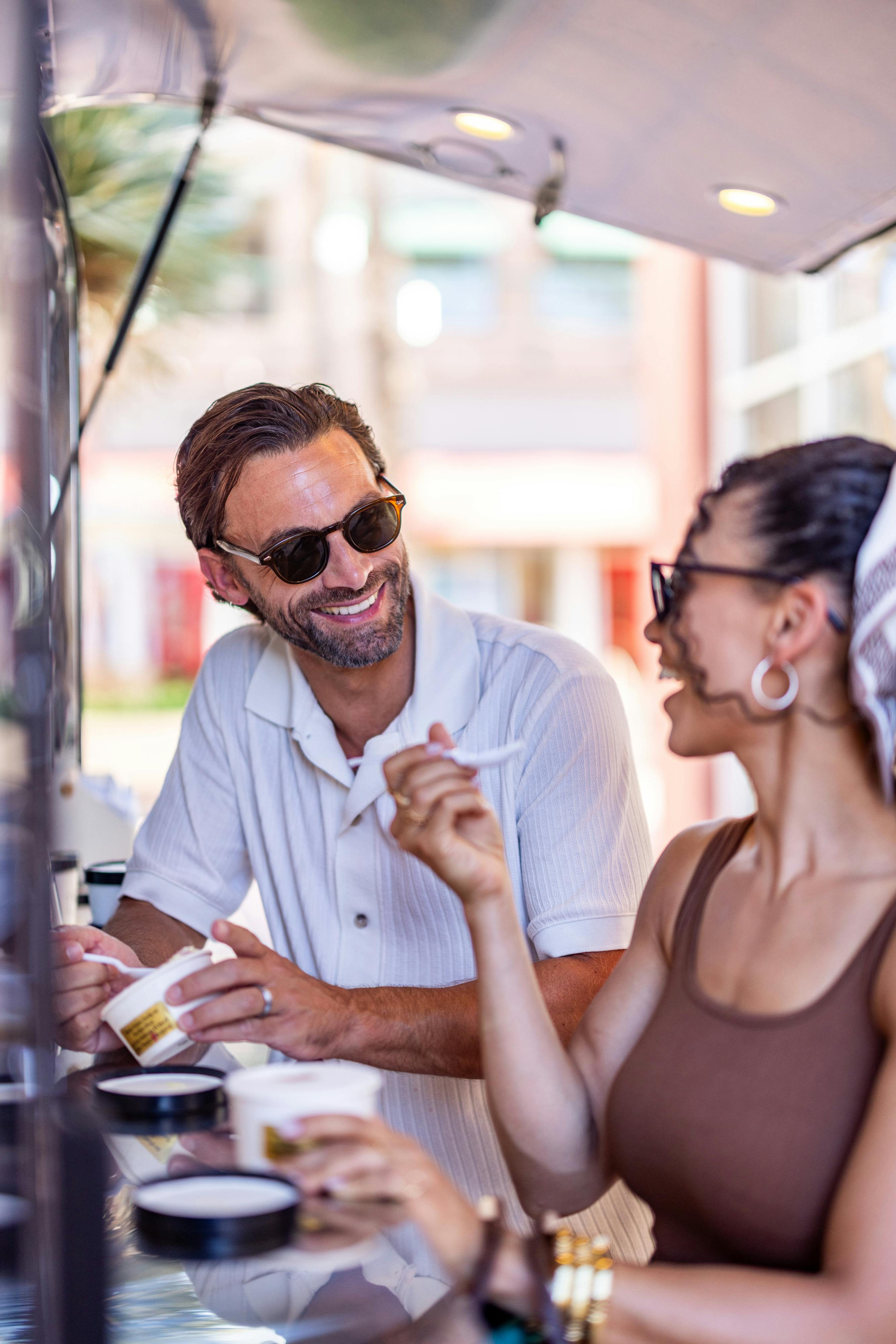 Couple connecting over ice cream in a sunny cafe.