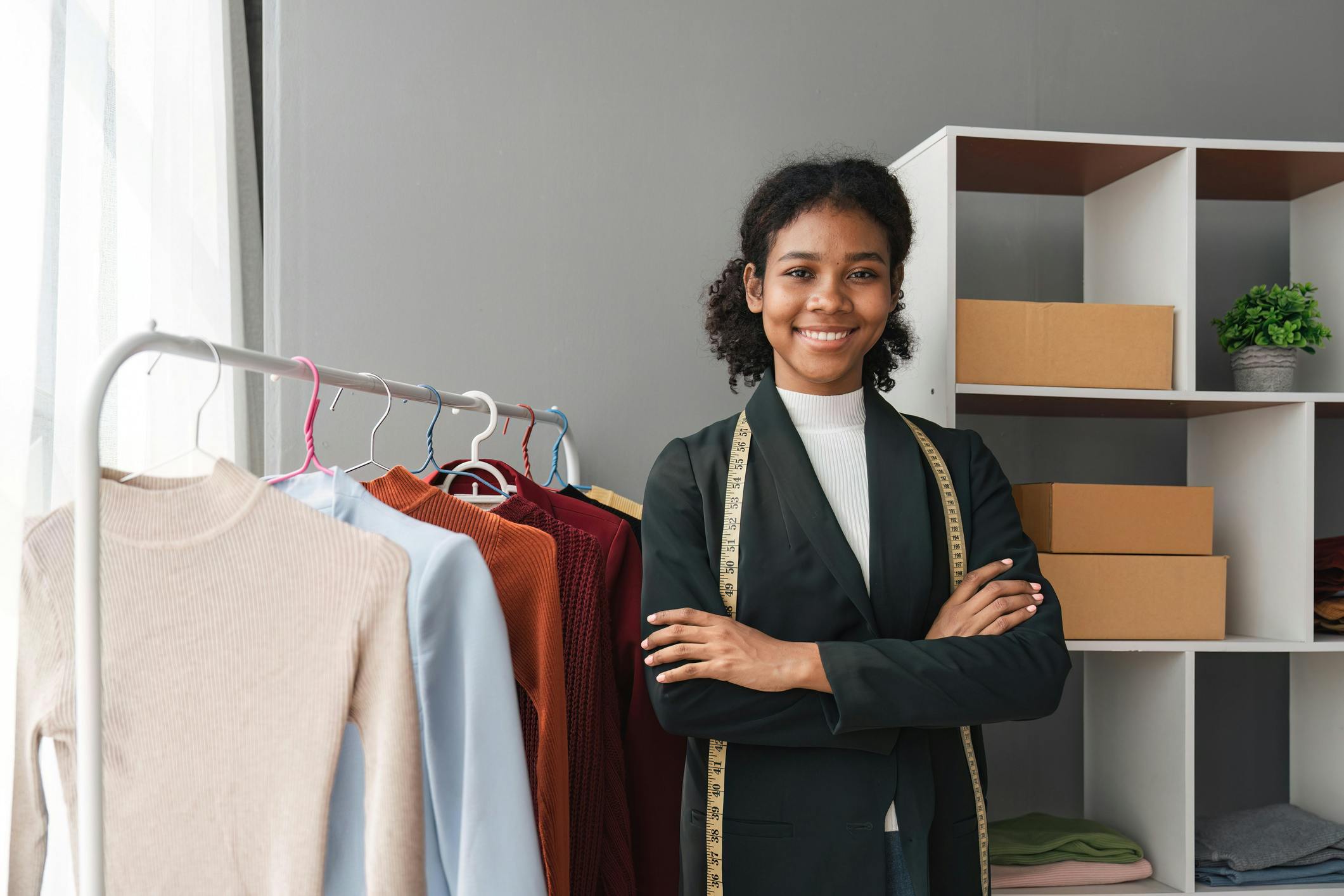 Student standing in front of a rack of clothing with a measuring tape draped over her neck