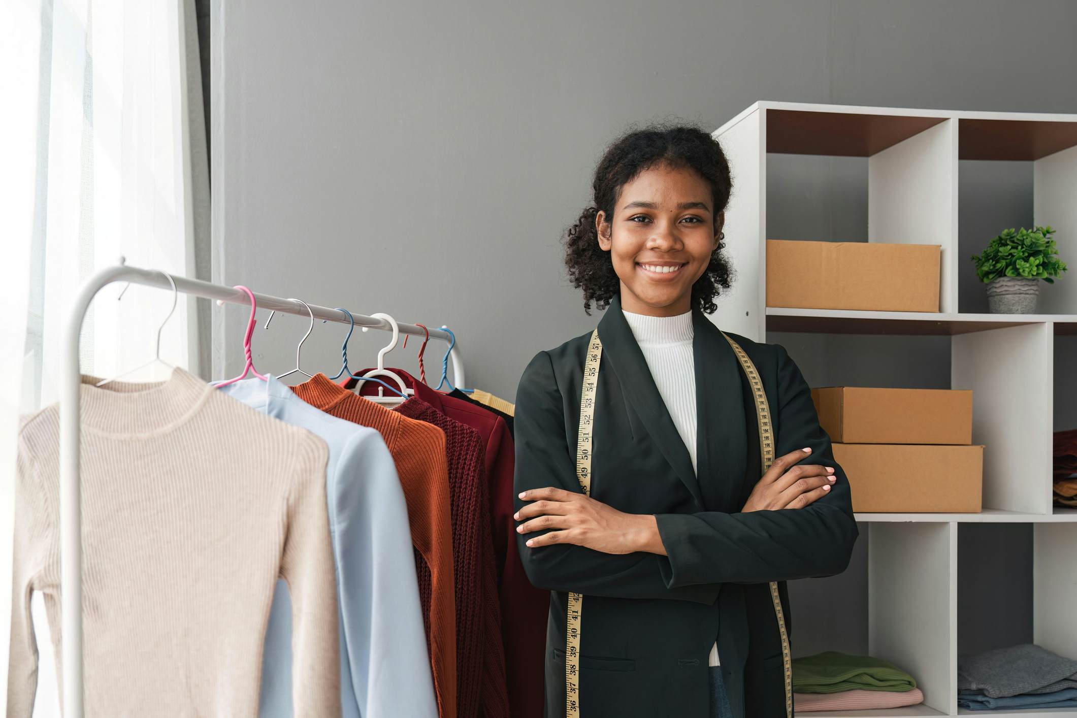 Student standing in front of a rack of clothing with a measuring tape draped over her neck