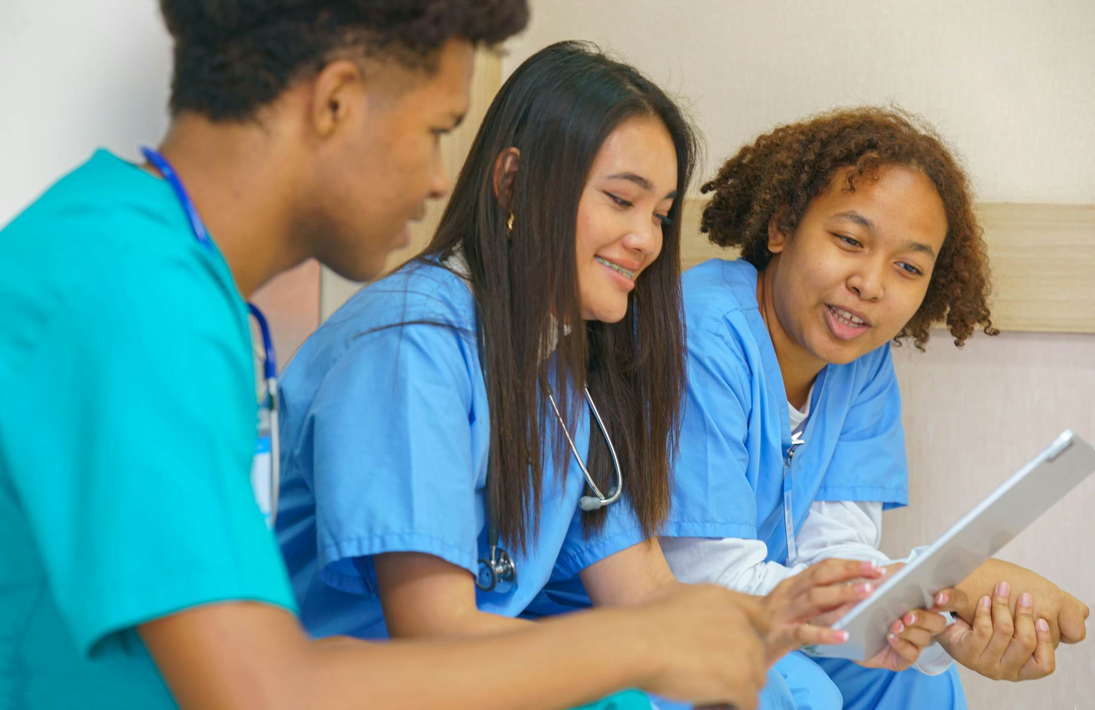 Three medical students looking at patient records on a tablet together