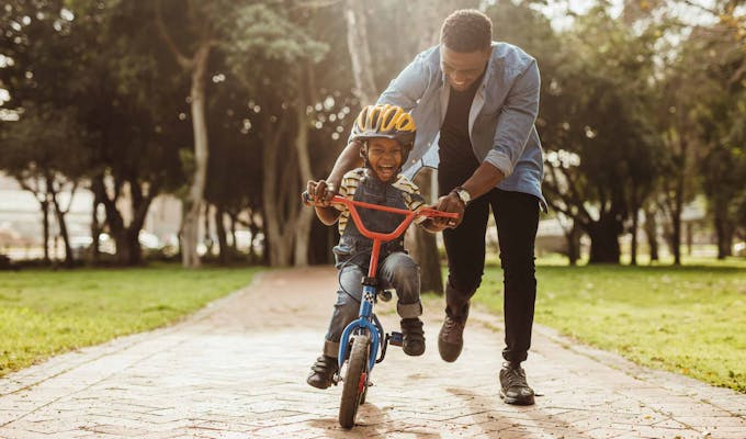 Dad teaching son to ride a bike.