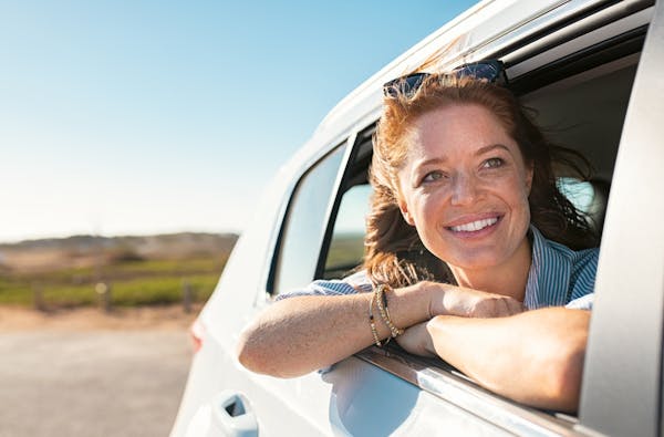 woman looking out care window smiling