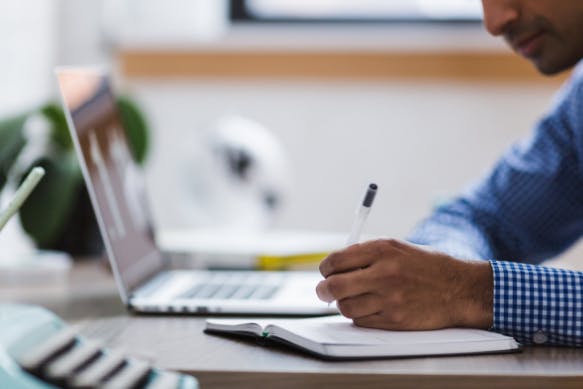 User on a laptop writing notes