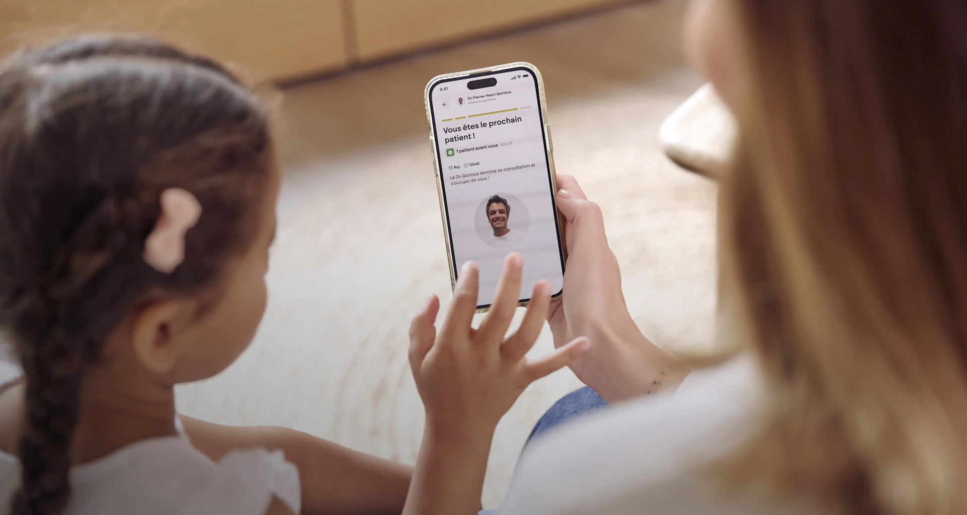 In a welcoming medical practice, a doctor and a young patient check the live waiting time on the Primary app.