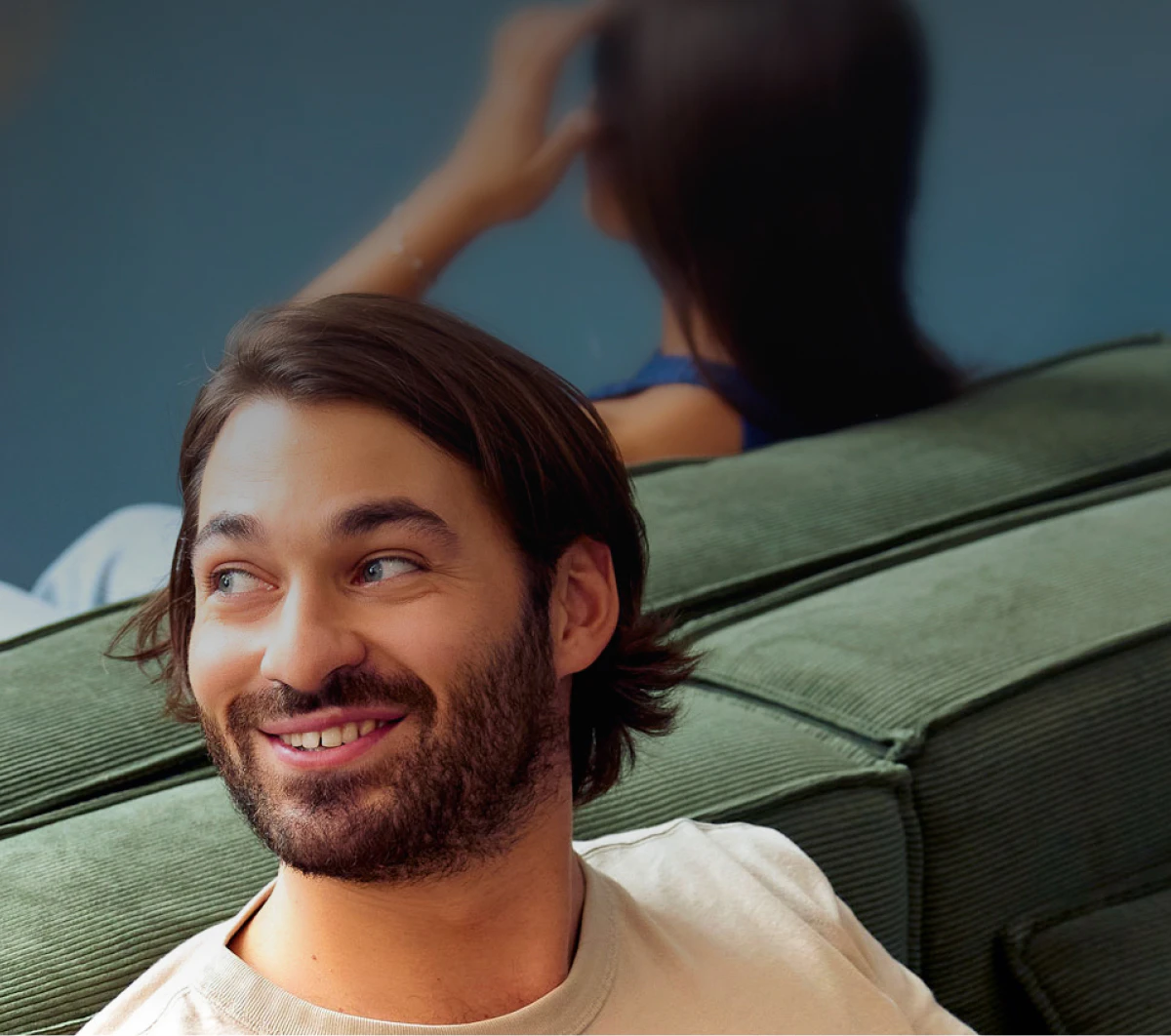 A patient in his twenties, sitting on a green velvet sofa, smiles when the doctor calls his name.