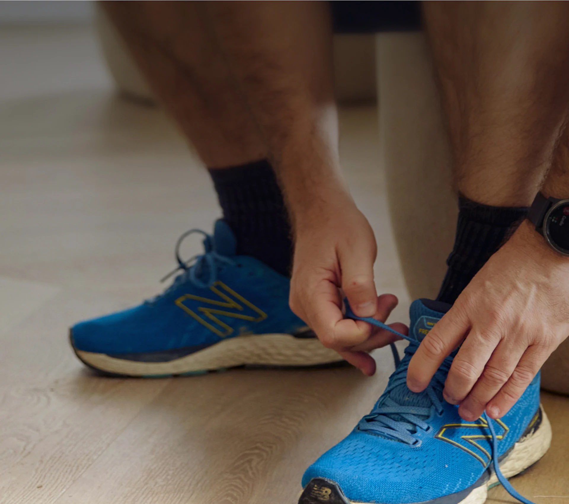Close-up of a man tying his running shoes before a workout, illustrating Primary's commitment to prevention