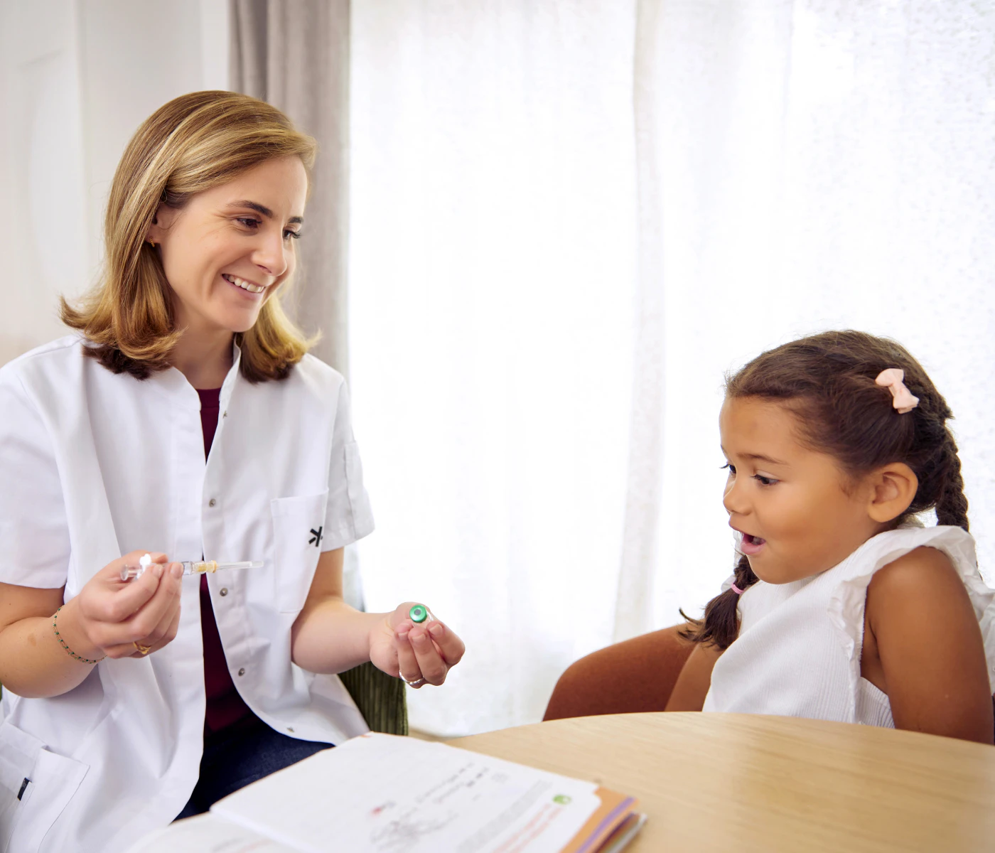A smiling doctor explains a medical procedure to a captivated and reassured little girl