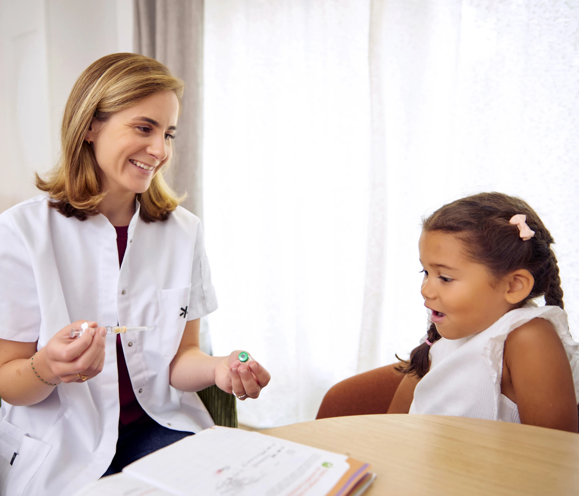 A smiling doctor explains a medical procedure to a captivated and reassured little girl
