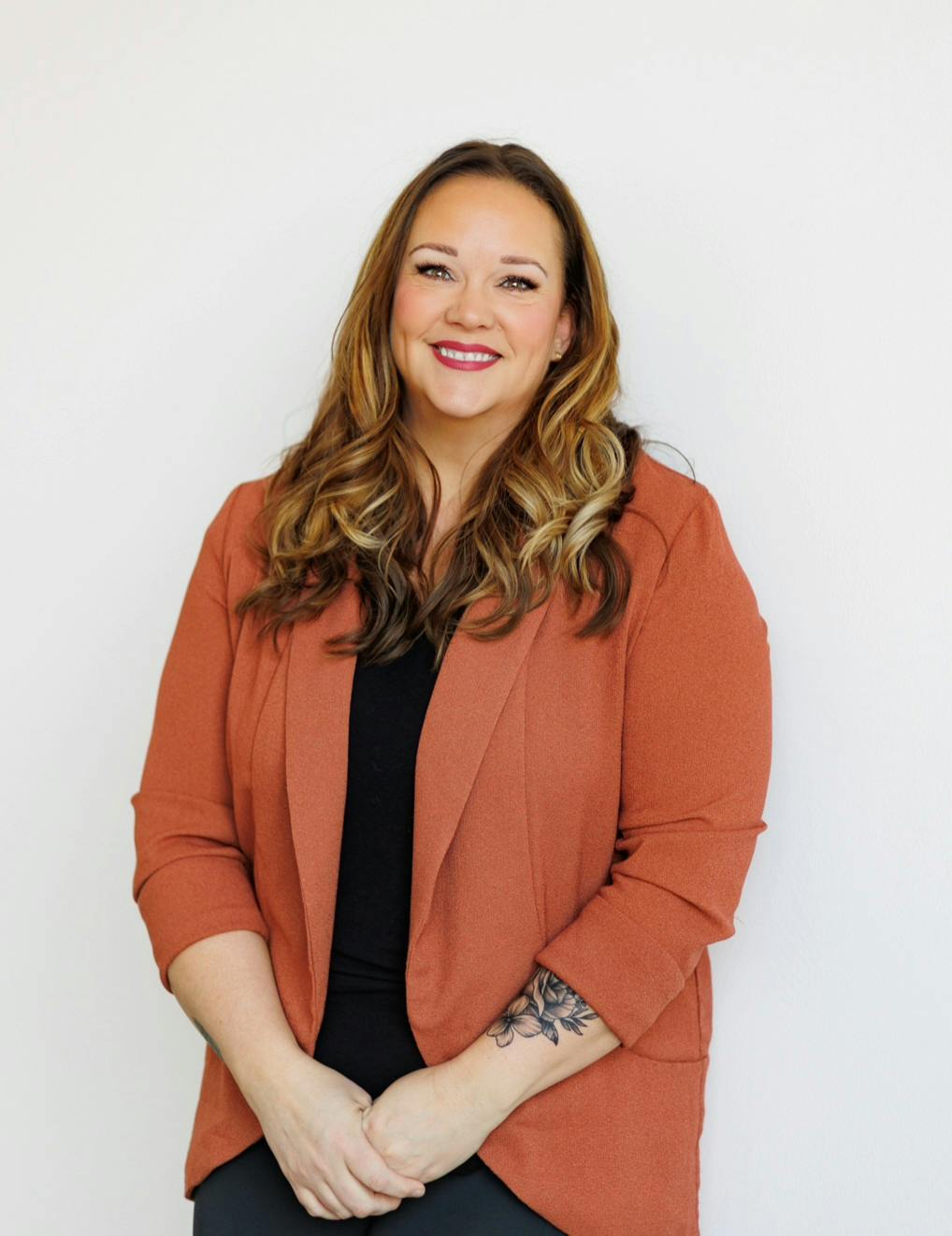Woman in orange blazer smiling at camera