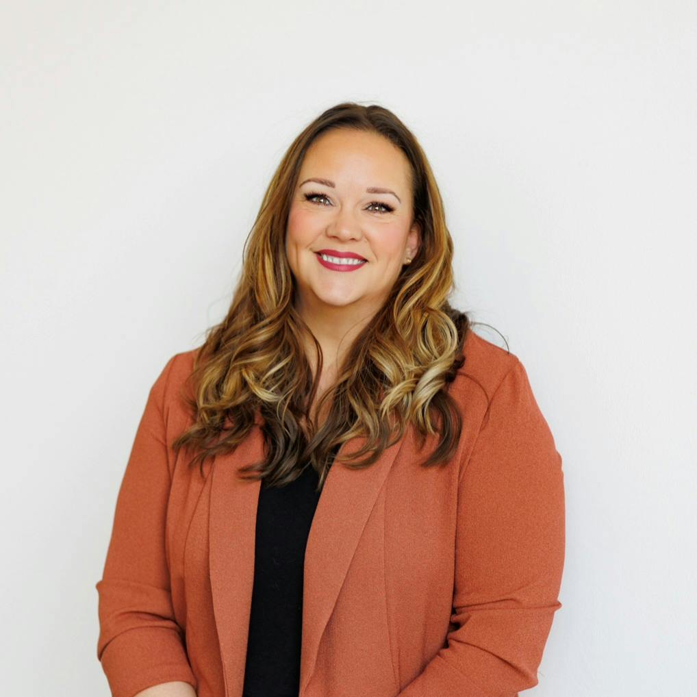 Woman in orange blazer smiling at camera
