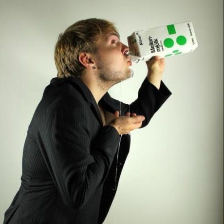 A playful portrait of Marcus drinking from a carton that's spilling over, taken from an artistic side view.