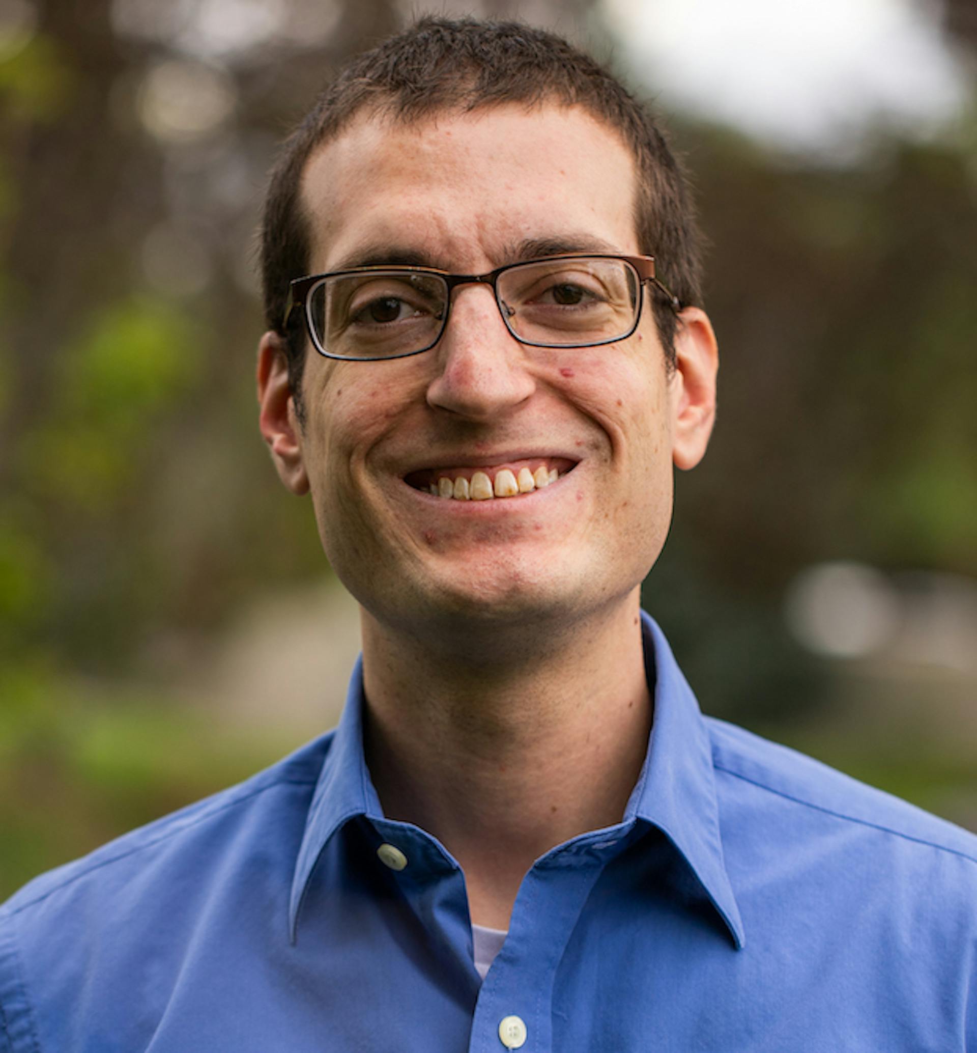 A portrait of Anthony Campolo in a blue shirt, smiling.