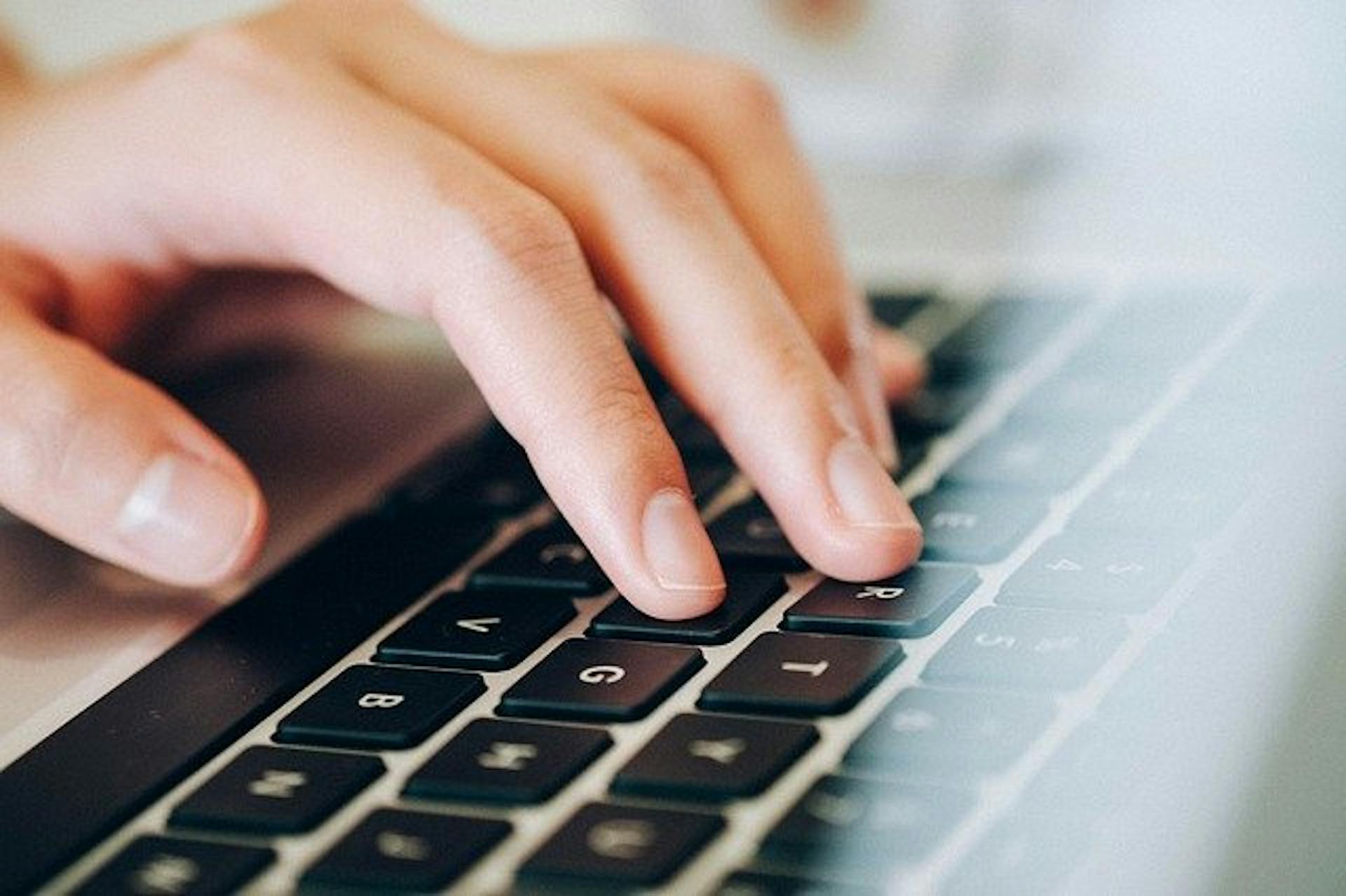 Hand resting on a Macbook keyboard.