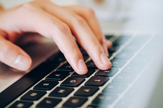 Hand resting on a Macbook keyboard.