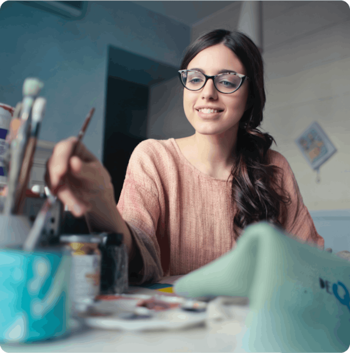 A smiling woman in glasses painting 