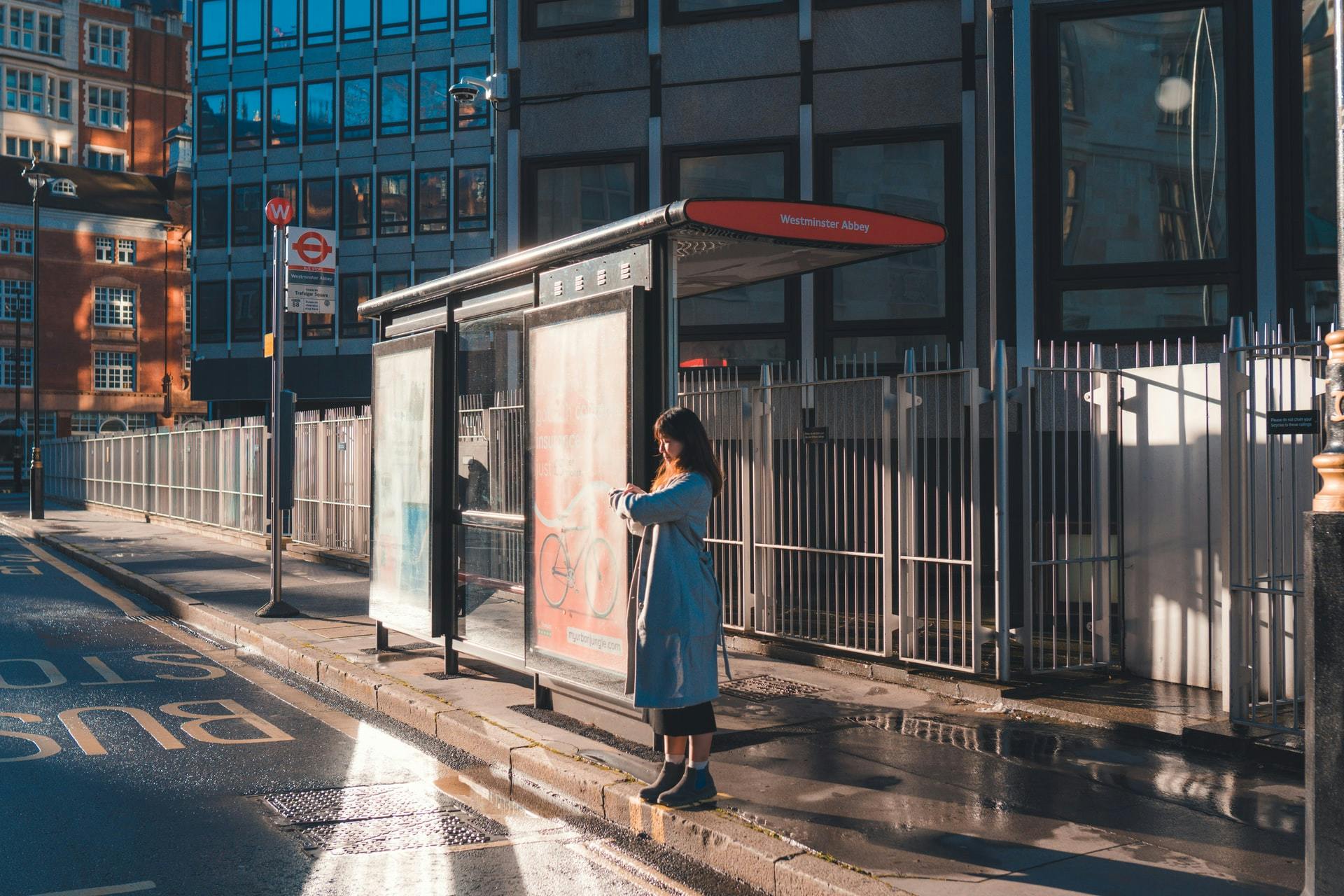 A woman standing at a bus stop