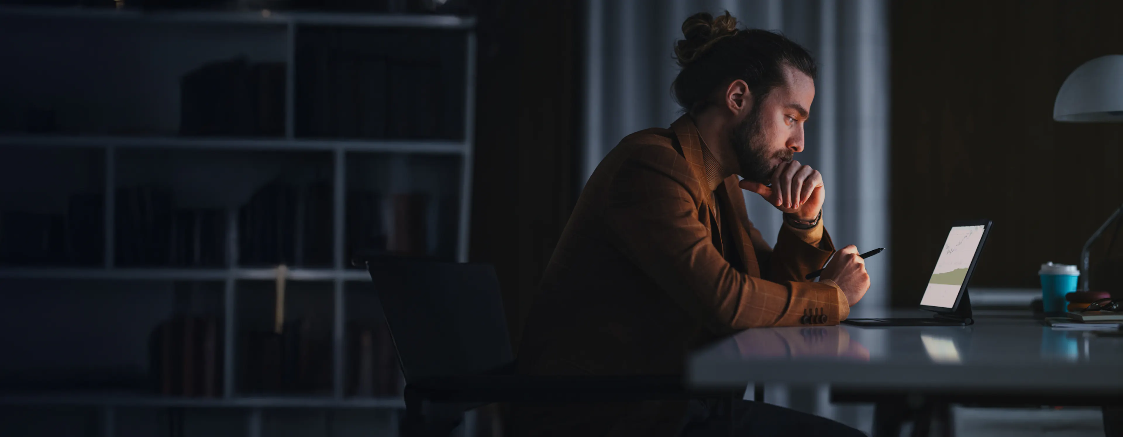  a man sitting in the dark looking at a tablet screen