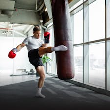 Man kick boxing with boxing gloves on and working out in Qatar gym