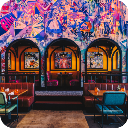 Bright and vibrant dining area at Central Abu Dhabi with a wall covered in graffiti, with separate booths for guests