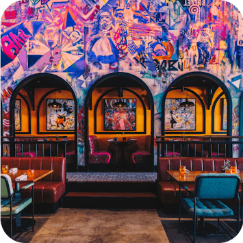 Bright and vibrant dining area at Central Abu Dhabi with a wall covered in graffiti, with separate booths for guests