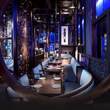 Atmospheric dark restaurant with blue lighting, creating a moody ambience, highlighting carefully arranged tables and seating.