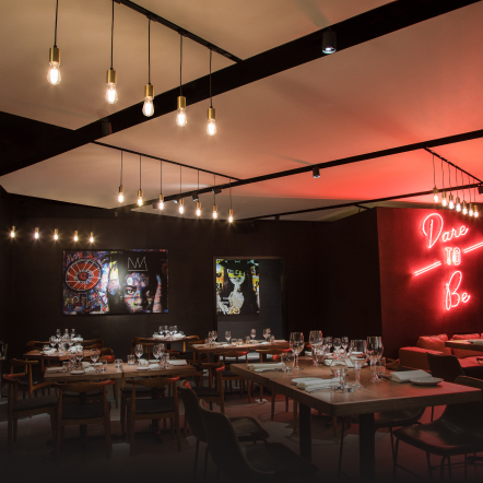 Dimly lit restaurant, furnished with art and neon signs  