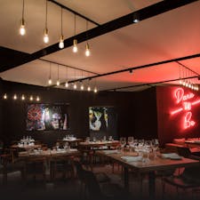 Dimly lit restaurant, furnished with art and neon signs  