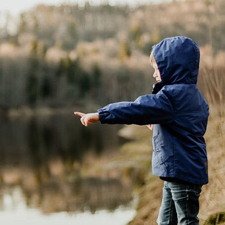 Ein Kind am See, das auf das Wasser zeigt