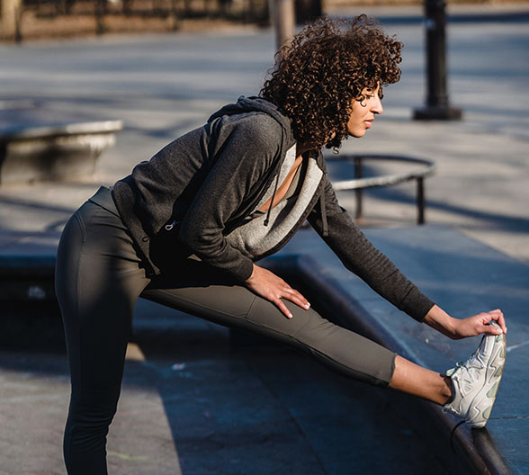 Eine Frau, die gerade Dehnungsübungen mit ihrem linken Bein macht