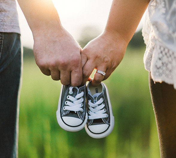 Ein Pärchen, das gemeinsam in den Händen ein paar Kinderschuhe hält. 