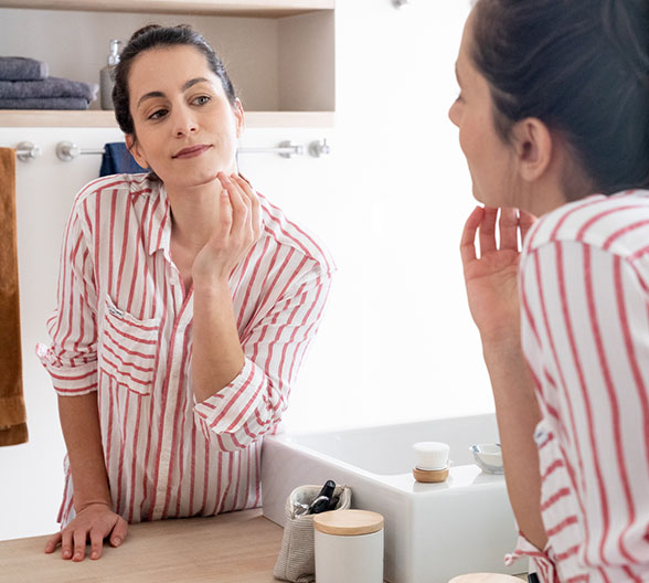 Eine Frau, die im Spiegel ihr Gesicht betrachtet