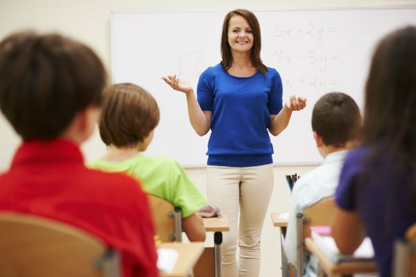 A teacher stands at the front of her class, trying to build excitement by previewing interesting parts of the day's lesson.