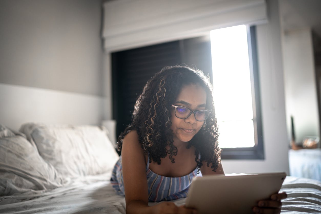 Child reading in bed through a reading app on her iPad