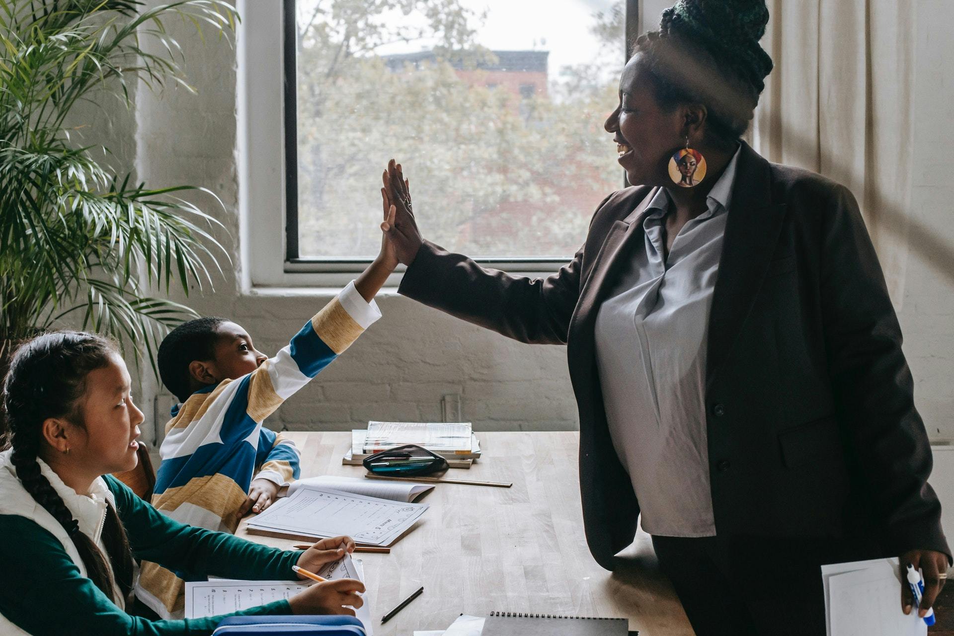 A teacher high-fives a student in her classroom as she teaches elementary math.