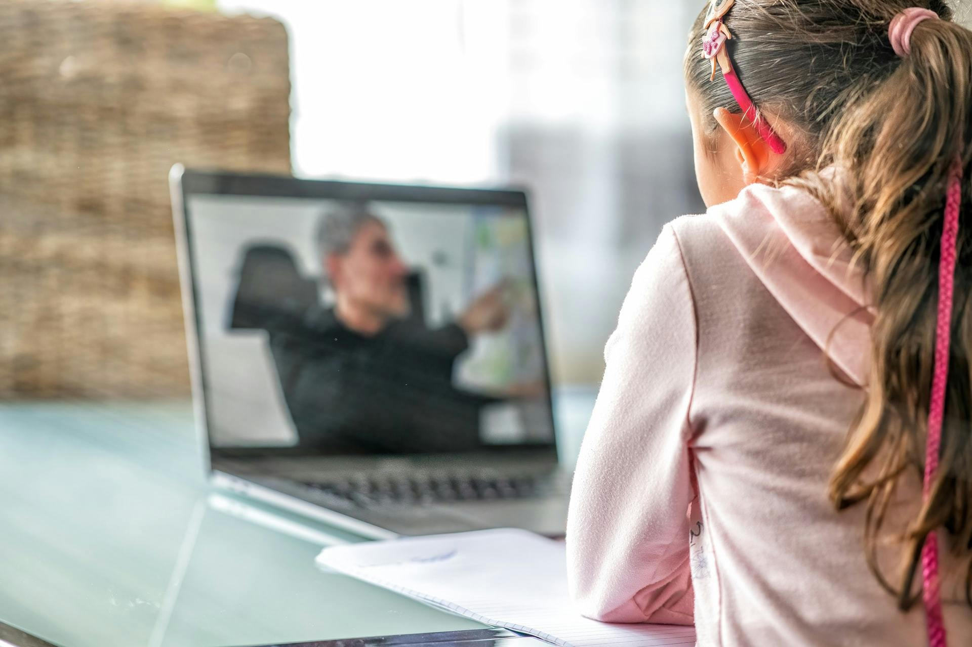 Young girl watches a teacher through a virtual classroom.