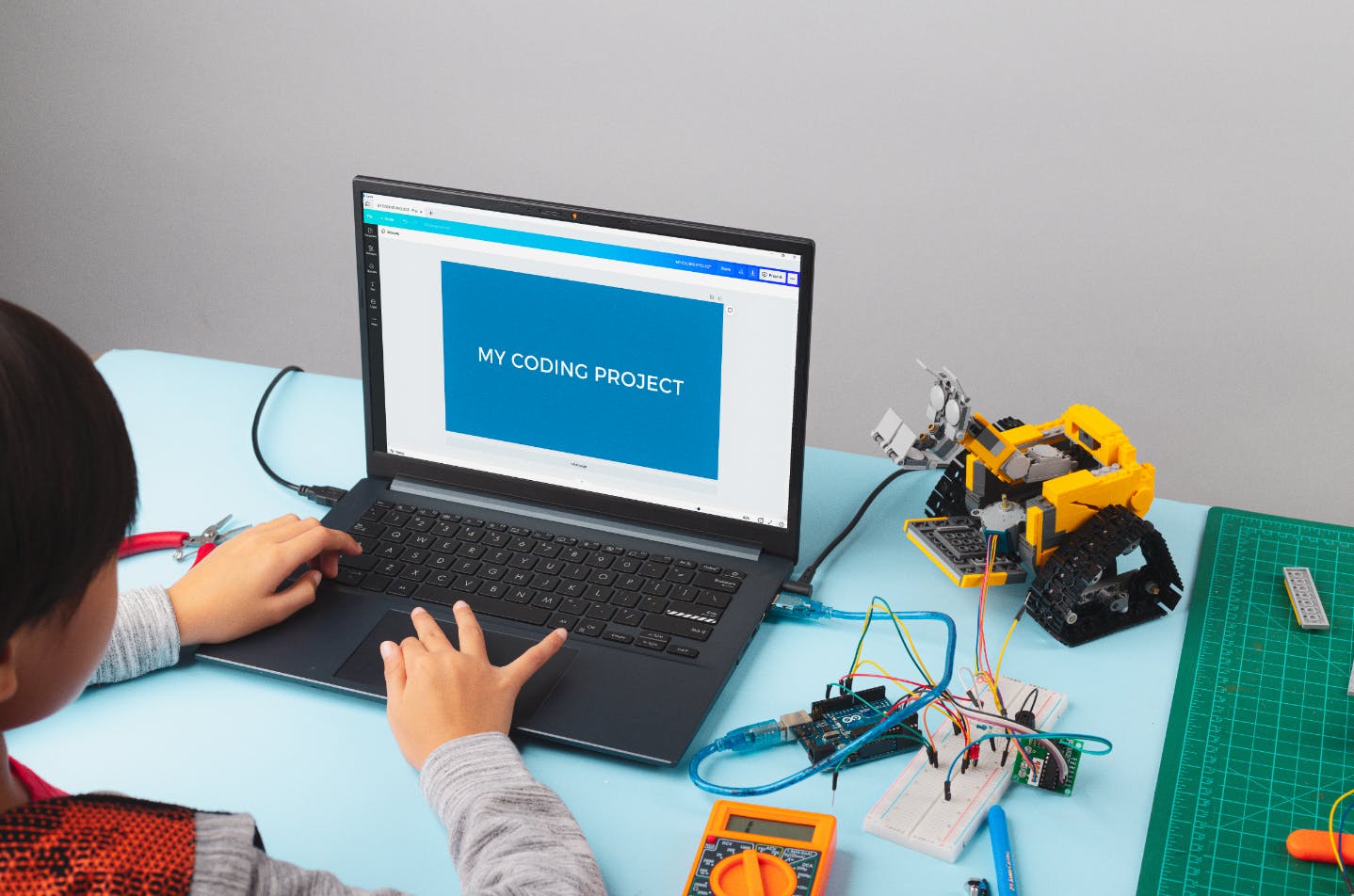 Child doing a coding program at their computer. Computer screen reads: "my coding project."