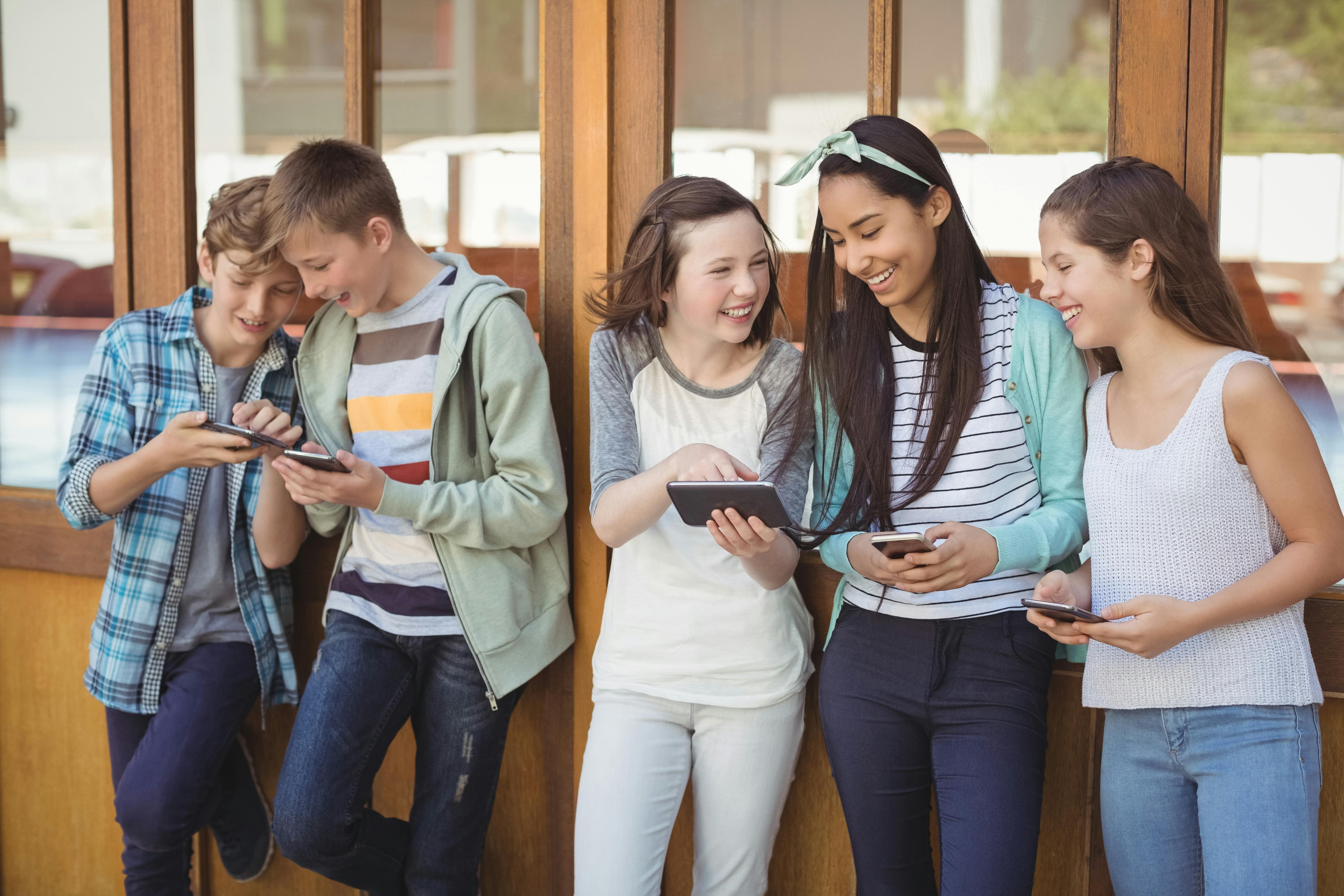 a group of preteens talking on phones