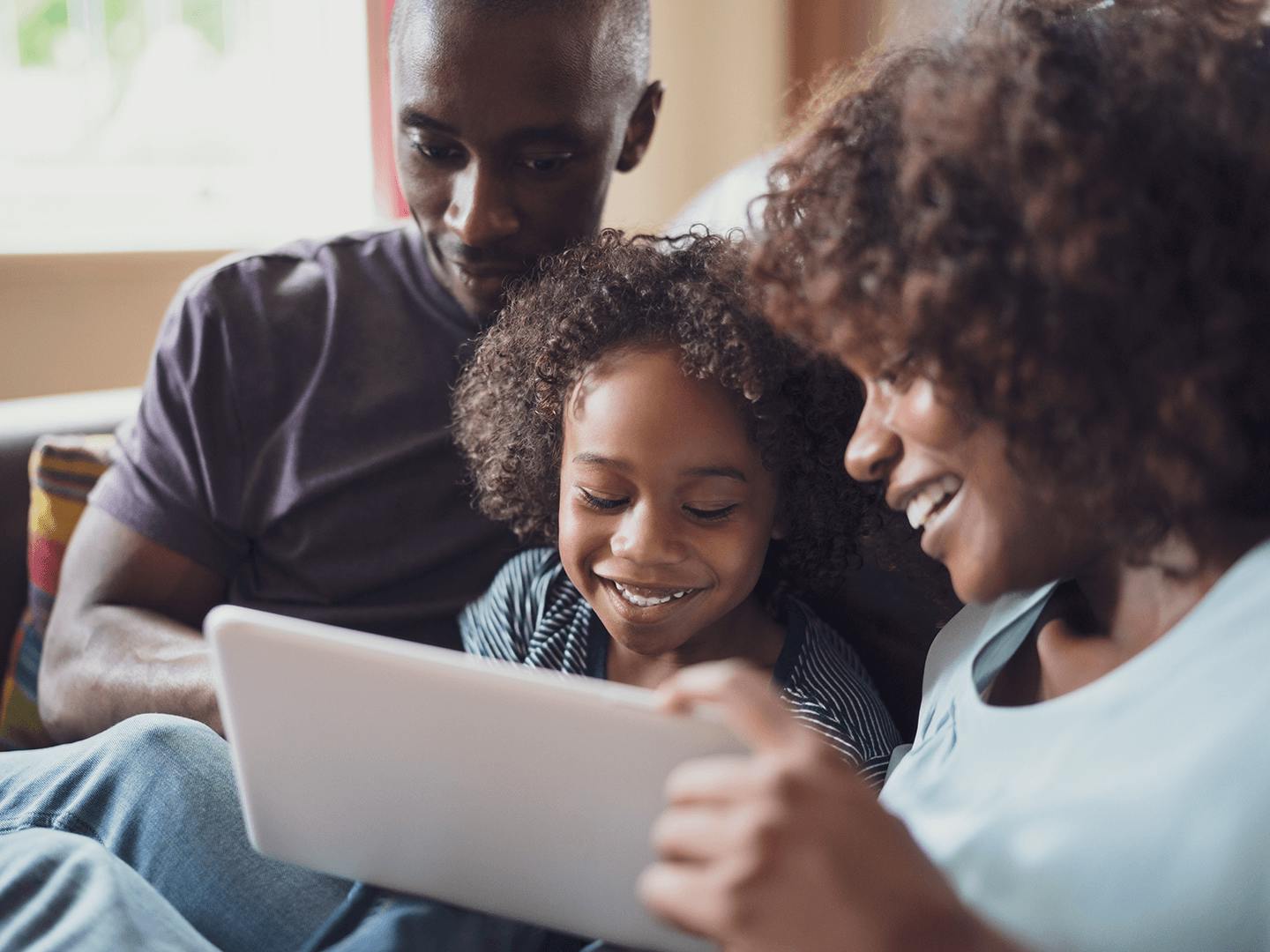 Child and her parents looking at a tablet device together.