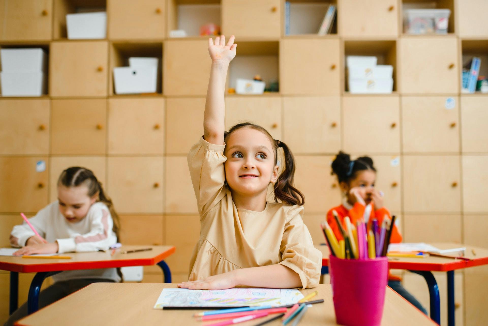 Young student raises her hand in class.