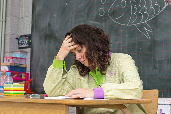 Teacher looking stressed at desk.