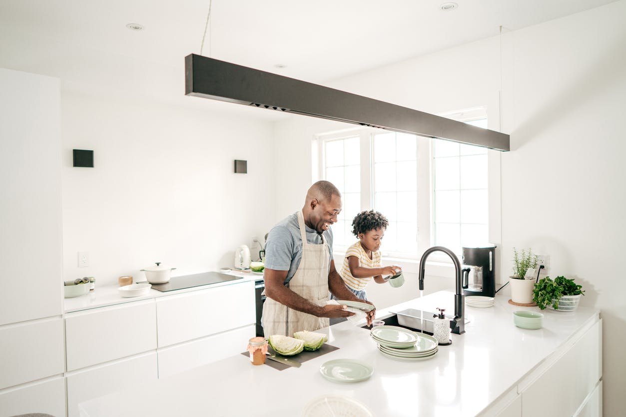 Child and father in the kitchen, following their family goal to cook together.