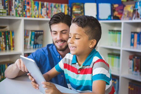 Teacher using tablet with student in class.