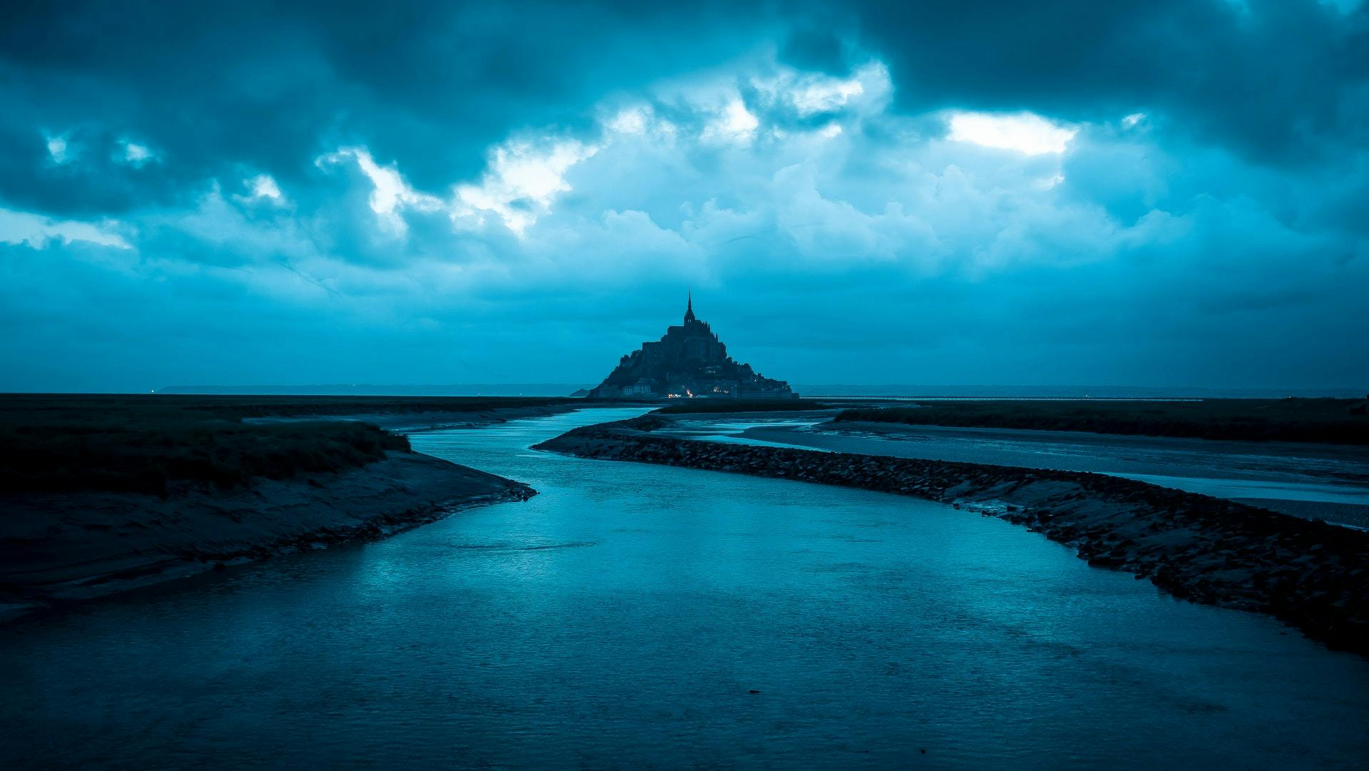 Dramatic shot of a castle from a distance across a river. 